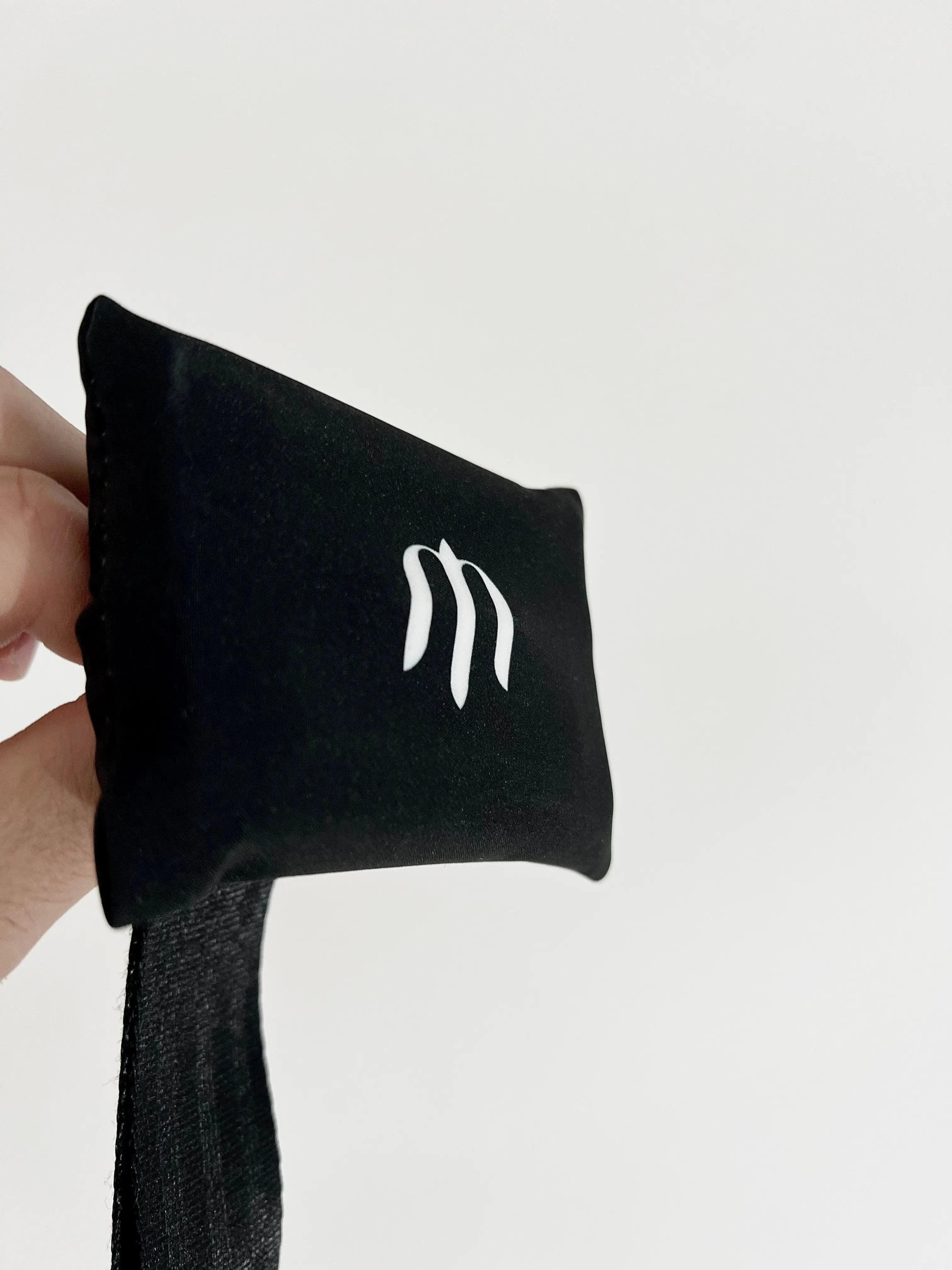 Black sock with a white logo held by a hand against a light gray background