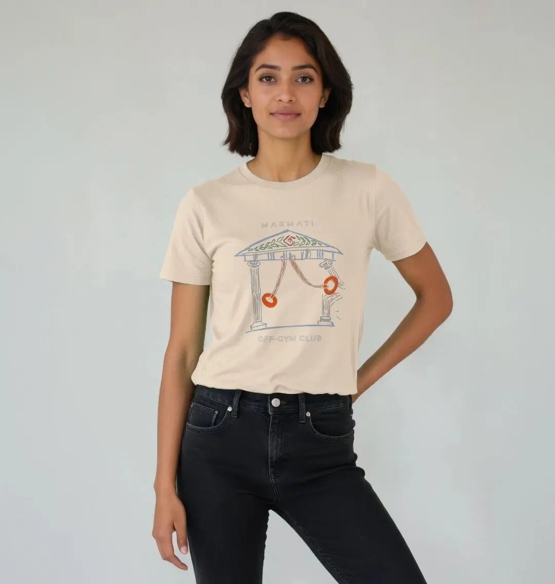 A woman wearing a beige t-shirt with a graphic print of gymnastic rings and a structure, paired with black pants.
