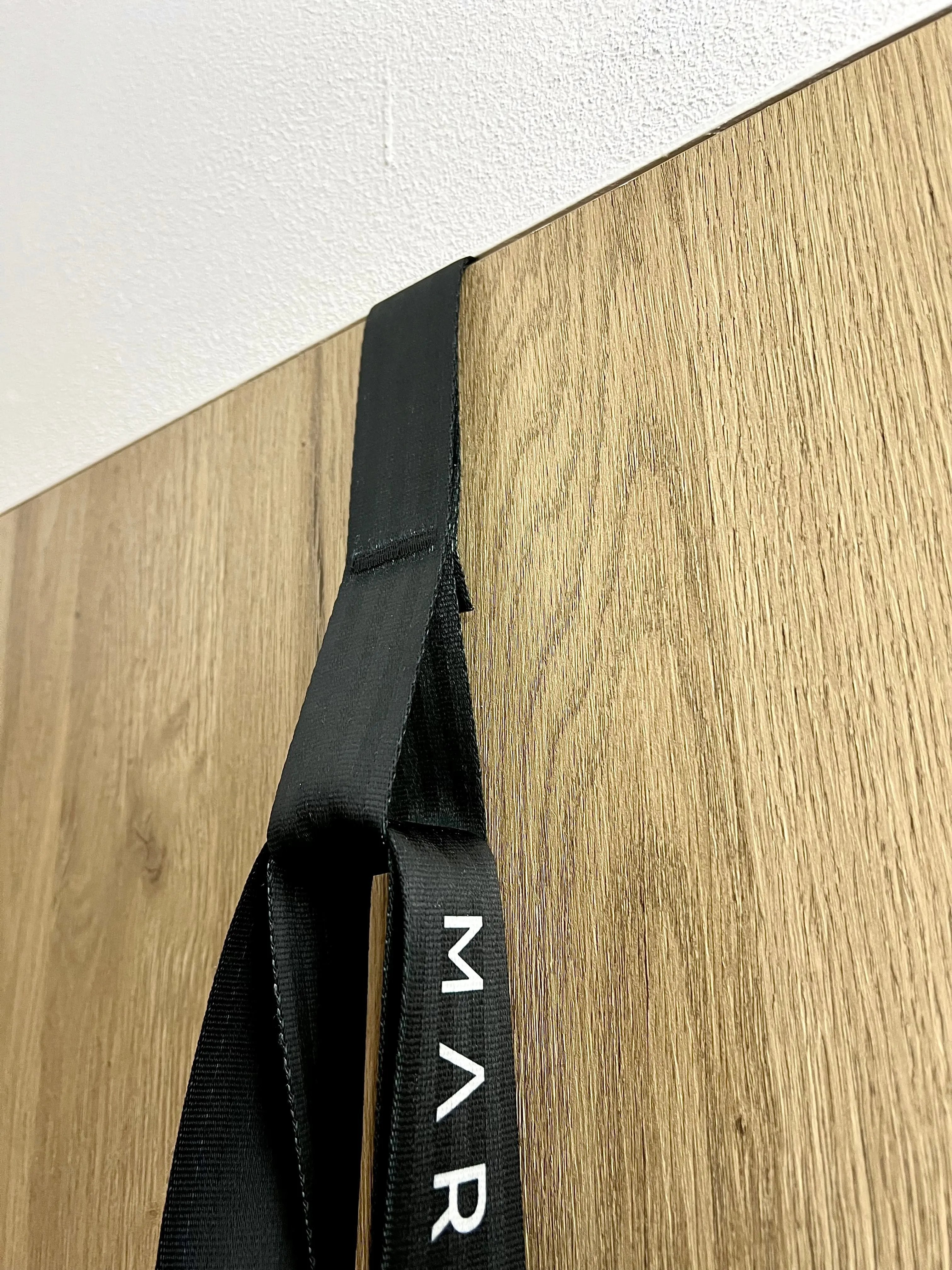 Black strap with 'MAR' logo on a wooden surface